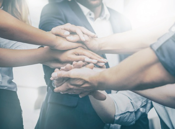 diverse group of co-workers with their hands piled together in a show of teamwork and togetherness